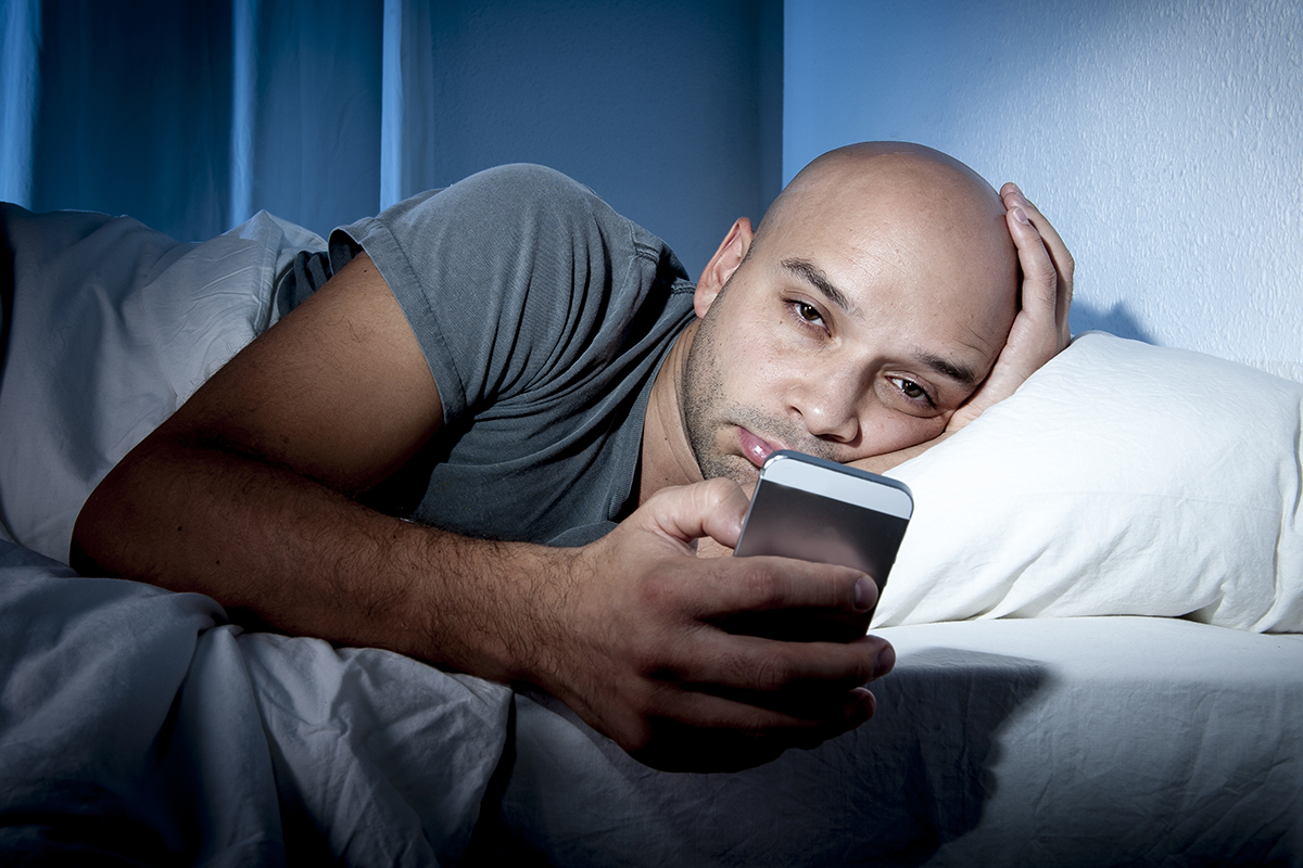 man awake on phone blue light disturbing his sleep